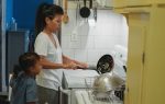 Una mujer cocinando mientras un niño está a su lado.